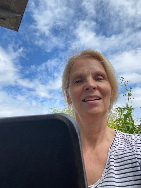 Frau vor iPad sitzend vor blauem Himmel