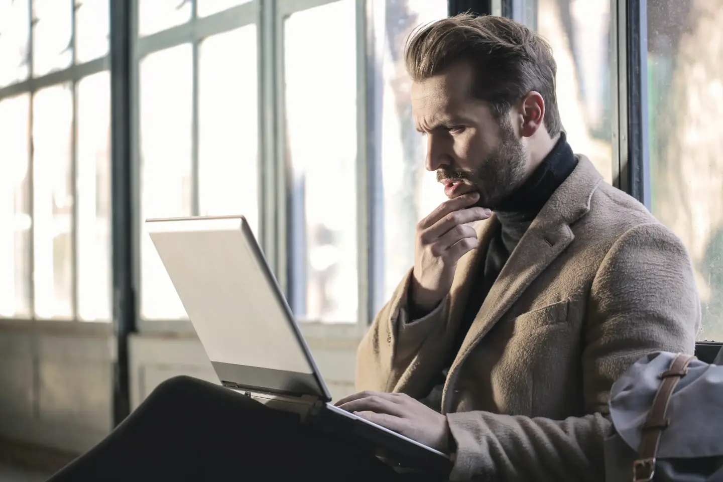 Mann sitzt grübelnd am Laptop